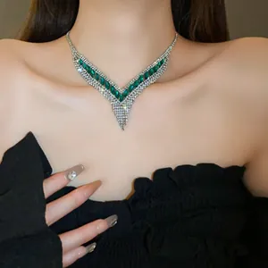 Détail des pierres vert émeraude et strass argentés sur le collier en forme de V