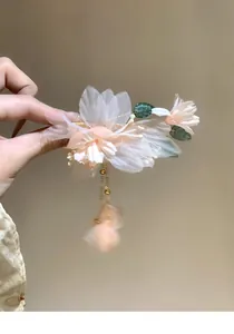 Close-up of elegant fabric flower hair clip with pearl accents and hanging tassel detail