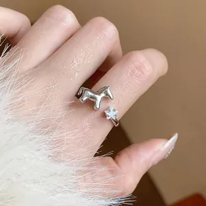 Macro detail of a silver horse and star zircon ring worn on a hand with fuzzy sleeve