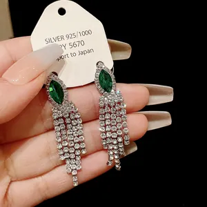 Vue détaillée des boucles d'oreilles à pompons en argent avec pierres précieuses