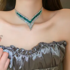 Gros plan d'un ras de cou vintage en V avec pierres précieuses vertes et strass brillants