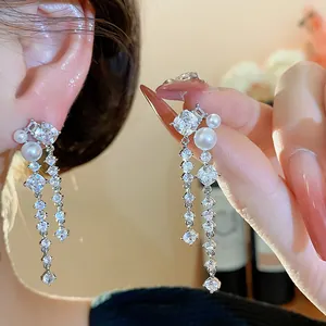 Close-up of elegant silver needle earrings with shimmering zirconia and white pearls