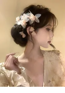 Close-up detail of an elegant fabric flower hair clip with tassels on a model's hair
