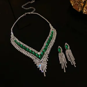 Détail d'un ensemble de bijoux vintage avec glands vert émeraude et strass.