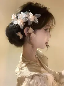 Elegant fabric flower hair clip with pearls and long tassels worn on a bun hairstyle