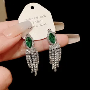 Gros plan détaillé de boucles d'oreilles marquise vert émeraude avec glands en cristal