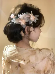 Elegant side view of a model wearing a delicate floral hair clip with pearls and tassels.