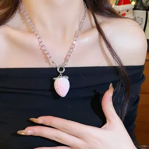 Dettaglio di una collana con ciondolo a fragola rosa su una modella.