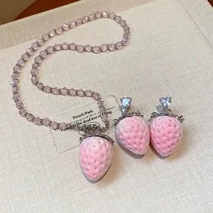 Dettaglio della collana fragola rosa floccata e orecchini a lobo in cristallo cuore
