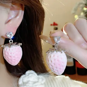 Primo piano di orecchini a fragola floccati rosa con perno in cristallo a cuore