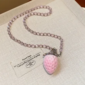Primo piano di un ciondolo a fragola rosa floccato e collana di perline di vetro