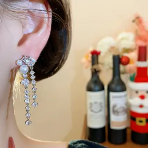 Detail shot of sparkling zircon and pearl drop earrings on model for festive look.