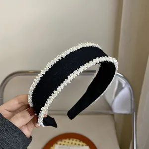 Detailed view of elegant black fabric headband with decorative white beaded trim