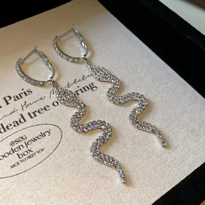 Elegant silver-toned snake-shaped dangle earrings encrusted with sparkling stones