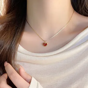 Close-up detail of an elegant red oil-drop heart pendant necklace worn by a female model