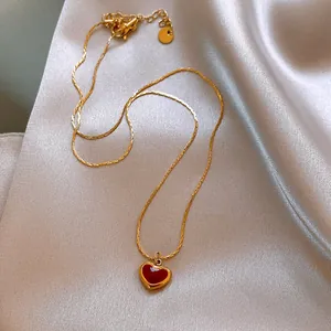 Detailed macro shot of a gold necklace featuring a vibrant red enamel heart pendant.