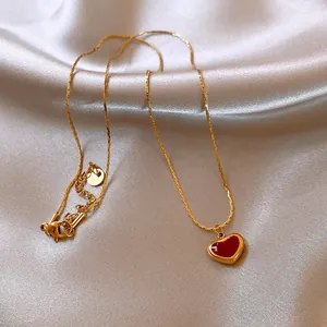 Detailed view of an elegant gold chain necklace featuring a red oil heart pendant