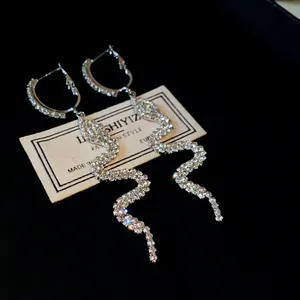 Detailed macro view of snake-shaped long drop earrings with pave set rhinestones.