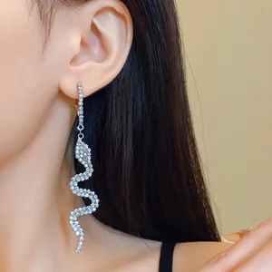 Elegant rhinestone-encrusted snake long dangle earrings on a female model's ear.