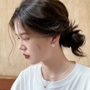 Elegant large round pearl stud earrings with high luster worn by an Asian model in profile