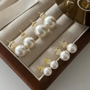 Set of elegant round white pearl stud earrings with high luster presented in a wooden box