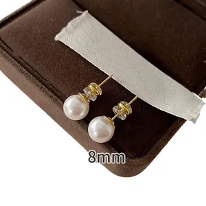 Elegant 8mm round white pearl stud earrings with golden finish in a premium jewelry box.