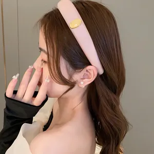 Close-up of a stylish pink sponge headband with a gold oval accent worn by a model