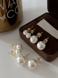 Detailed view of high-luster pearl stud earrings in various sizes on a jewelry box