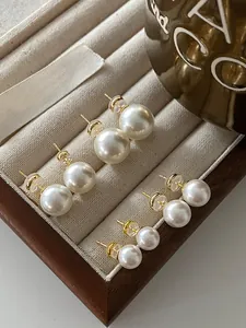 Set of four pairs of round pearl stud earrings in varying sizes displayed in a tray