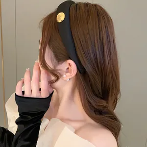Close-up of a stylish black padded sponge headband with a gold oval accent