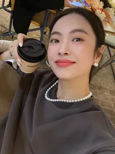 Elegant round white pearl stud earrings and matching necklace worn by an Asian model