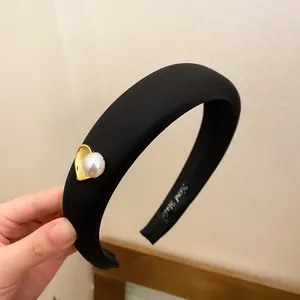 Detailed macro view of black padded sponge headband featuring gold heart and pearl