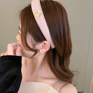 Pink padded headband with gold heart and pearl detail worn by model for elegant look
