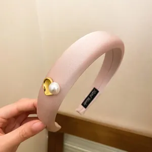 Detailed macro view of a pink padded sponge headband featuring a gold heart and pearl