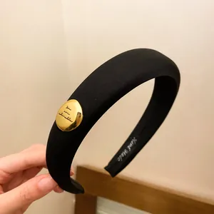 Close-up of black sponge headband with golden 'You are adorable' oval charm