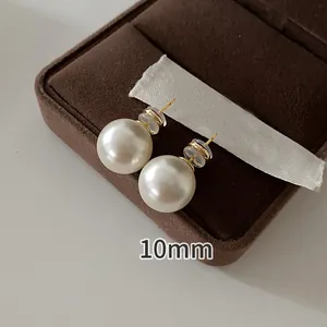 Detailed close-up view of 10mm round white pearl stud earrings on a velvet jewelry display