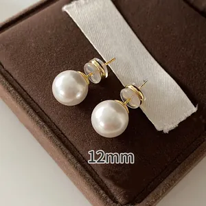 Detailed macro view of elegant 12mm round white pearl stud earrings on brown box