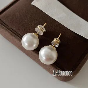 Detailed macro view of 14mm large round white pearl earrings on a jewelry box lid