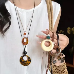 Détail de colliers vintage avec pendentifs en résine sur cordons de cire réglables.