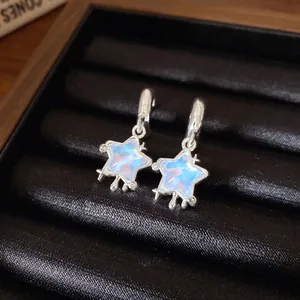 Orecchini a stella color argento con resina iridescente su un vassoio nero