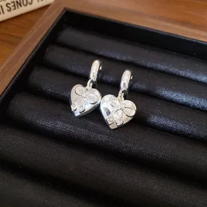 Macro di orecchini a cuore in argento con fiocco e pietre scintillanti in una scatola