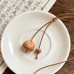Gros plan d'un collier rétro en corde cirée avec pendentif pomme de pin sur soucoupe.