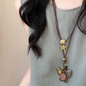 Gros plan d'un collier vintage en corde cirée avec perle en bois et pendentif papillon