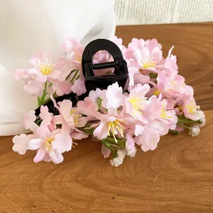 A high-detail shot showcasing the delicate pink fabric flowers on a black hair claw clip.