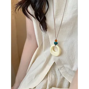 Collier rétro minimaliste avec anneau en résine crème et perles colorées sur cordon
