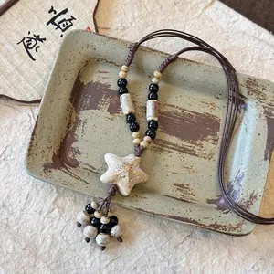 Détail rapproché du collier avec pendentif étoile fait main et perles en céramique.