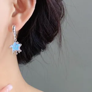 Primo piano di raffinati orecchini a stella in resina d'argento con finitura blu iridescente.