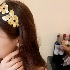 Dettaglio dell'elegante cerchietto in metallo dorato con farfalla indossato da una modella