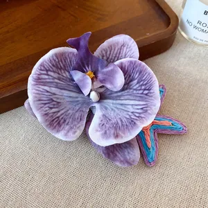 Detail of purple fabric orchid and colorful woven starfish hair clips on a linen surface