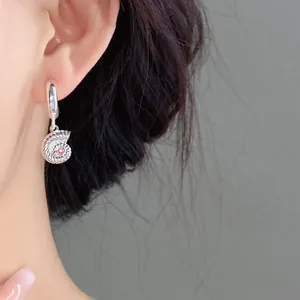 Dettaglio ravvicinato di un orecchino a conchiglia d'argento con zircone rosa centrale
